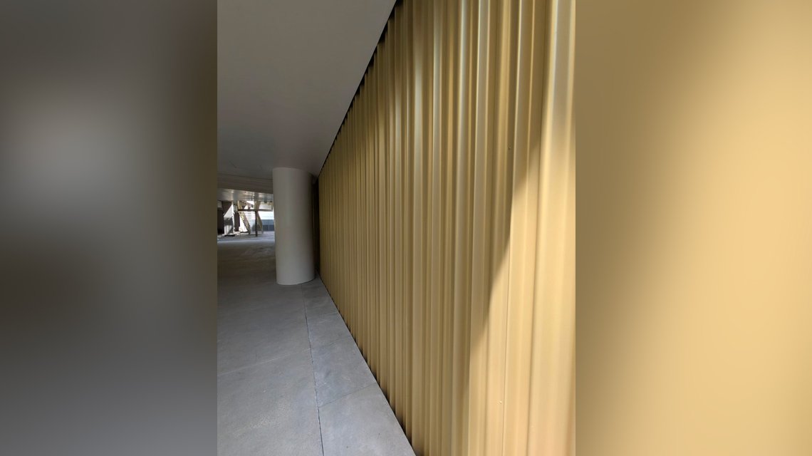 Tôle ondulée champagne en habillage mural Paris  - <p>Tôle ondulée champagne en habillage mural pour ce hall de bâtiment parisien. Réalisation sur mesure avec 3 modèles d’ondulation de notre fabricant.</p>