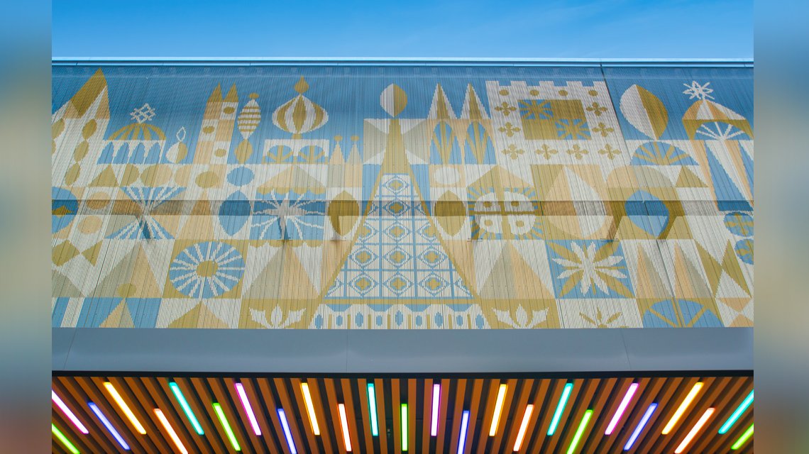 Façade métallique Kriskadecor Disney Village – Vue frontale complète - <p>Vue frontale de la façade en chaînes aluminium Kriskadecor installée au Disney Village (Disneyland Paris). Le panneau décoratif reproduit une composition graphique monumentale sur maillons anodisés, illustrant la capacité du matériau à habiller une façade commerciale avec légèreté, durabilité et haute personnalisation.</p>